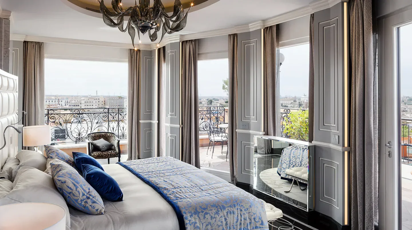 Luxury bedroom at Baglioni Hotel Regina in Rome with balcony overlooking the city.