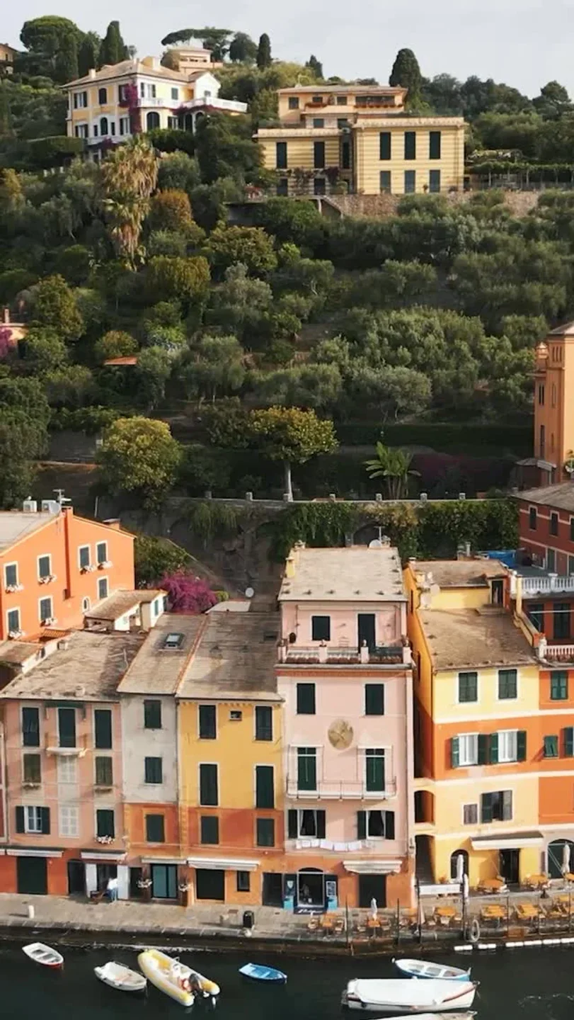 Colorful buildings line the waterfront in the Italian Riviera near Bagni Fiore, with boats in the water.