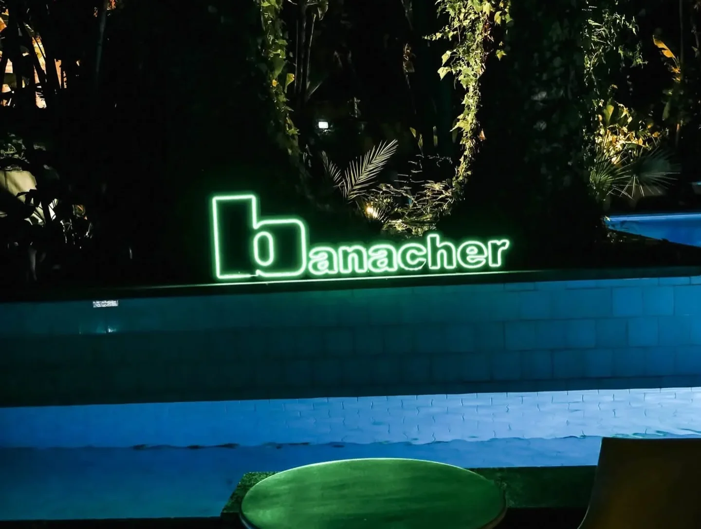 Banacher Club in Sicily at night with glowing neon sign and illuminated pool ambiance
