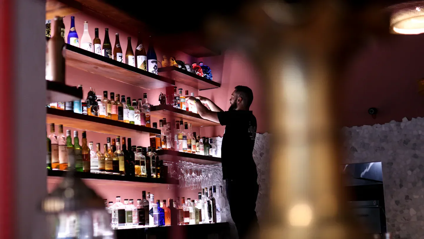 Interior of Bar Beirut in Canberra, with a bartender arranging bottles on shelves.