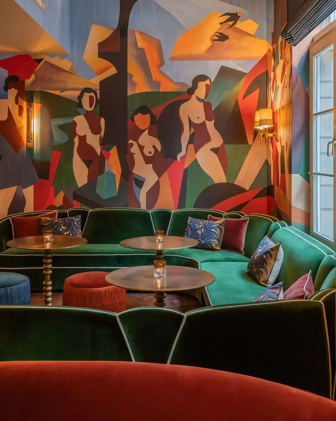 Interior of Bar Magritte in Brussels, featuring a velvet sofa and artistic mural.
