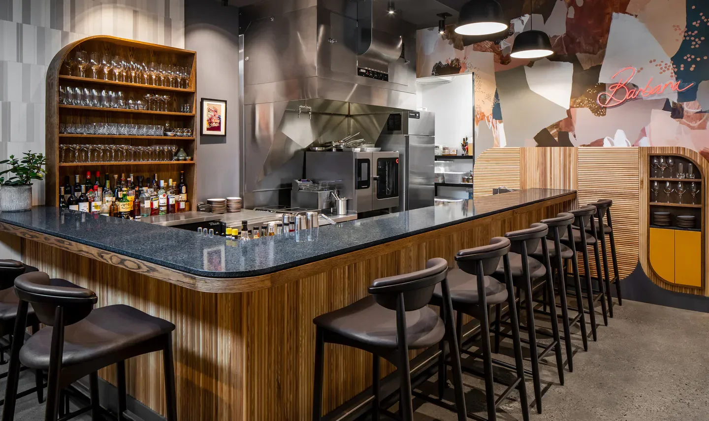 Stylish bar interior at Barbara restaurant in Vancouver with seating and open kitchen.