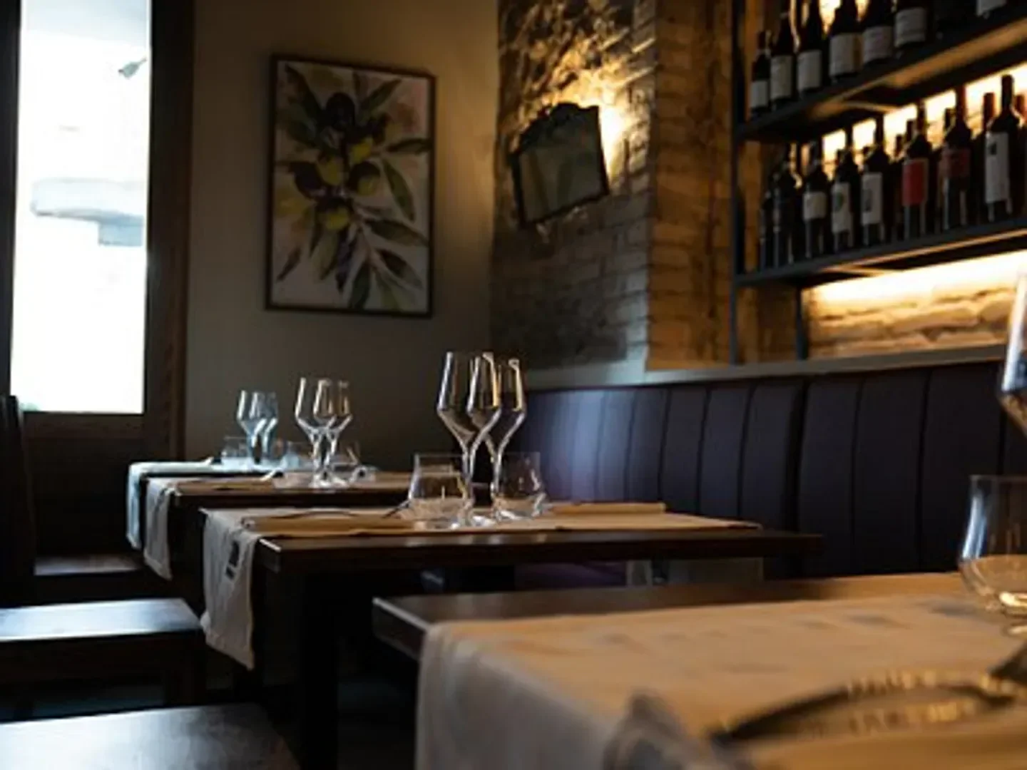 Interior dining scene at BARRED, a cozy restaurant in Rome, Italy, with wine glasses and tables.