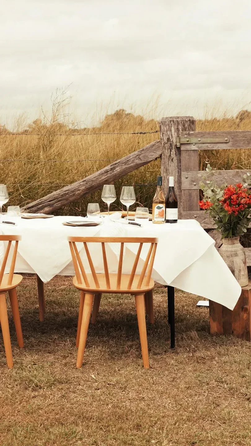 Outdoor dining table at Bask on the Sunshine Coast, set with wine glasses and flowers.