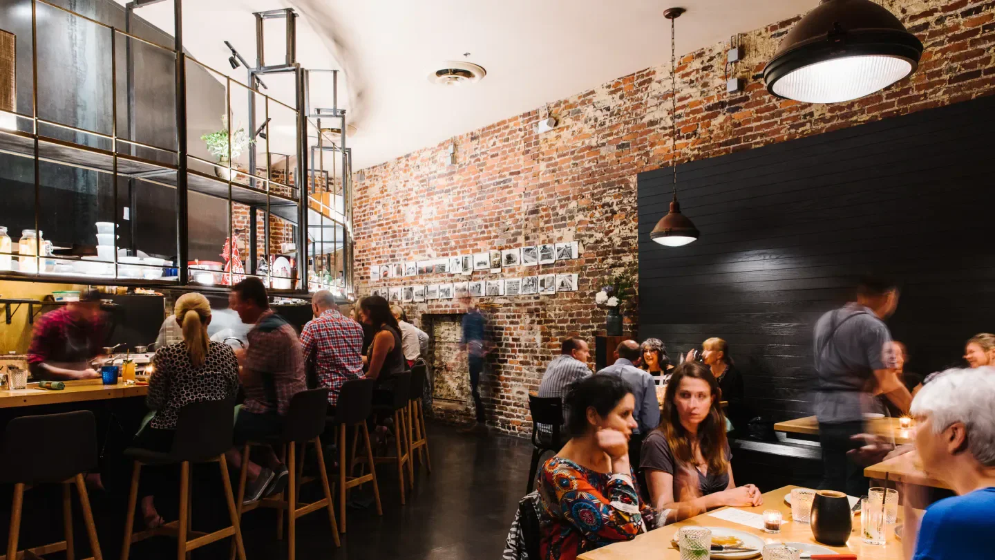Interior of Bastion restaurant in Nashville, with brick wall and dining patrons.