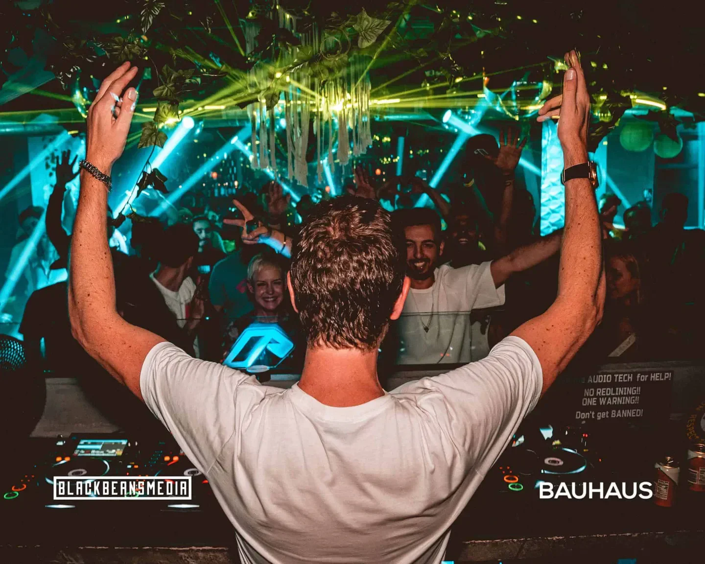 DJ at Bauhaus Houston nightclub, crowd dancing with hands raised, energetic atmosphere.