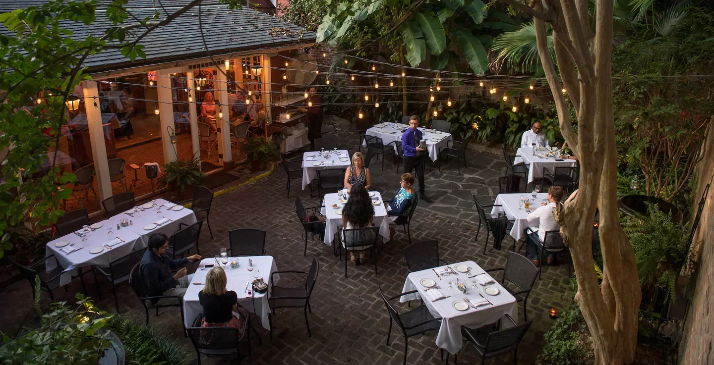 Outdoor dining at Bayona restaurant in New Orleans with elegant tables and string lights.
