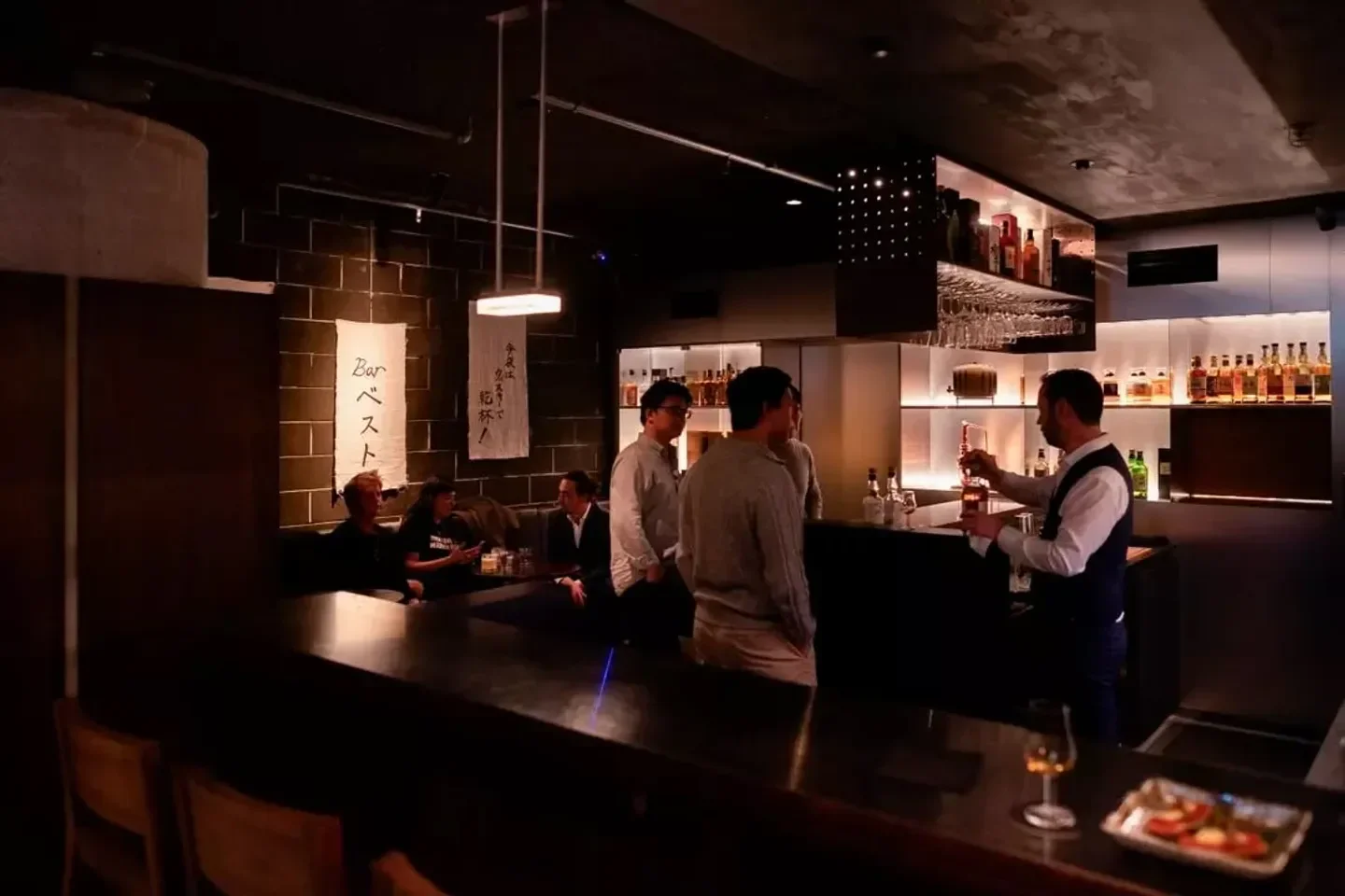 Interior bar scene at Besuto Omakase in Sydney, featuring a bartender and patrons.