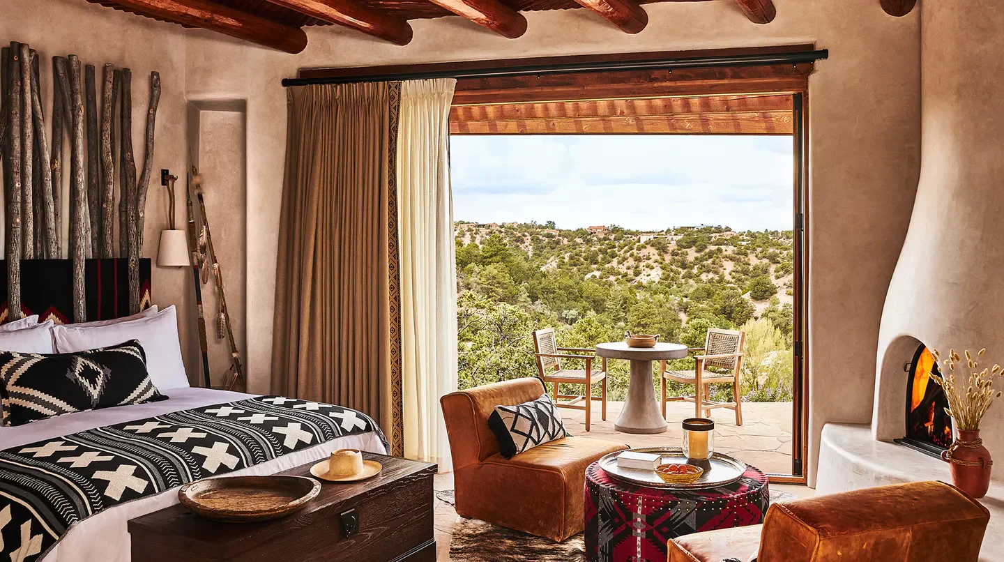 Cozy bedroom at Bishop's Lodge, Auberge Resorts Collection in Santa Fe, with fireplace and patio.