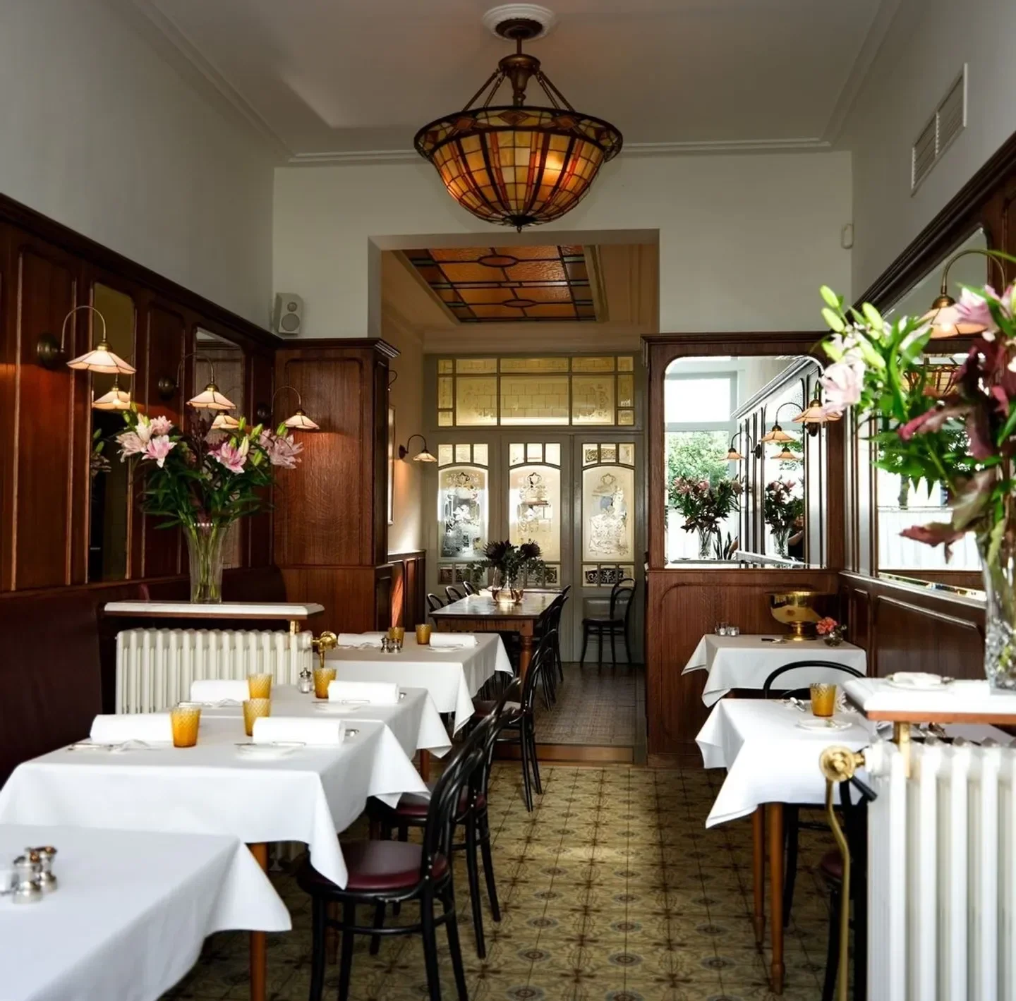 Elegant interior of Bistrot du Nord in Antwerp with tables set for dining.