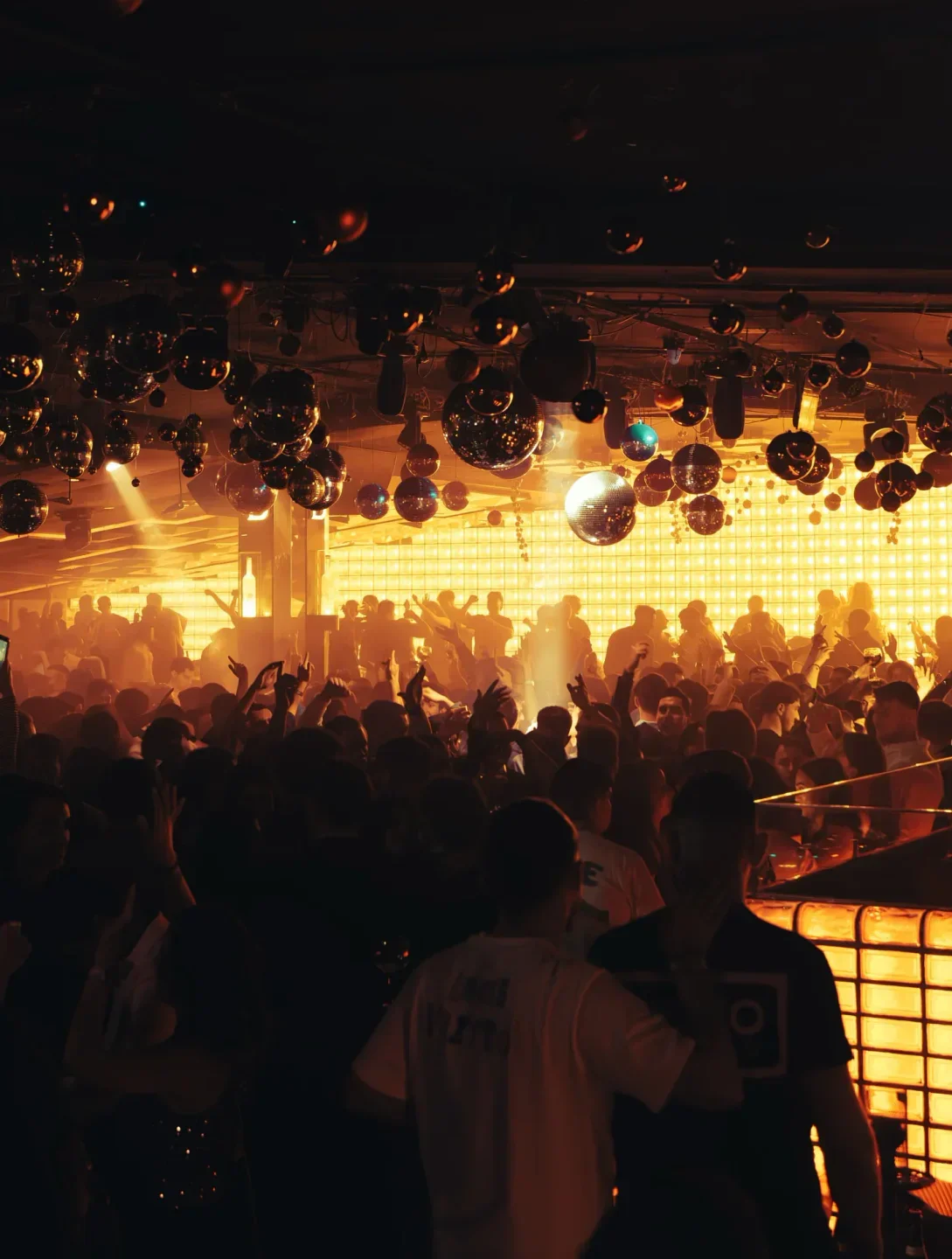 Energetic crowd partying at Bling Bling nightclub in Barcelona with disco balls.