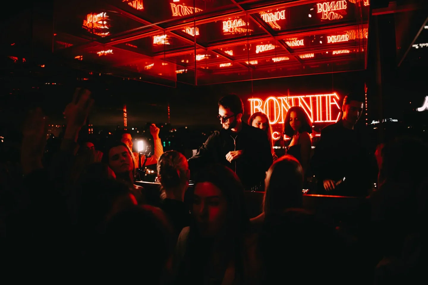Neon "BONNIE" sign illuminates a crowd at the nightclub in the city.