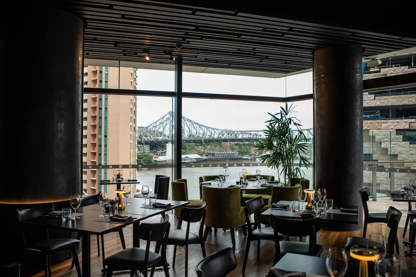 Interior of BŌS restaurant in Brisbane, with river and bridge views, elegant dining tables.