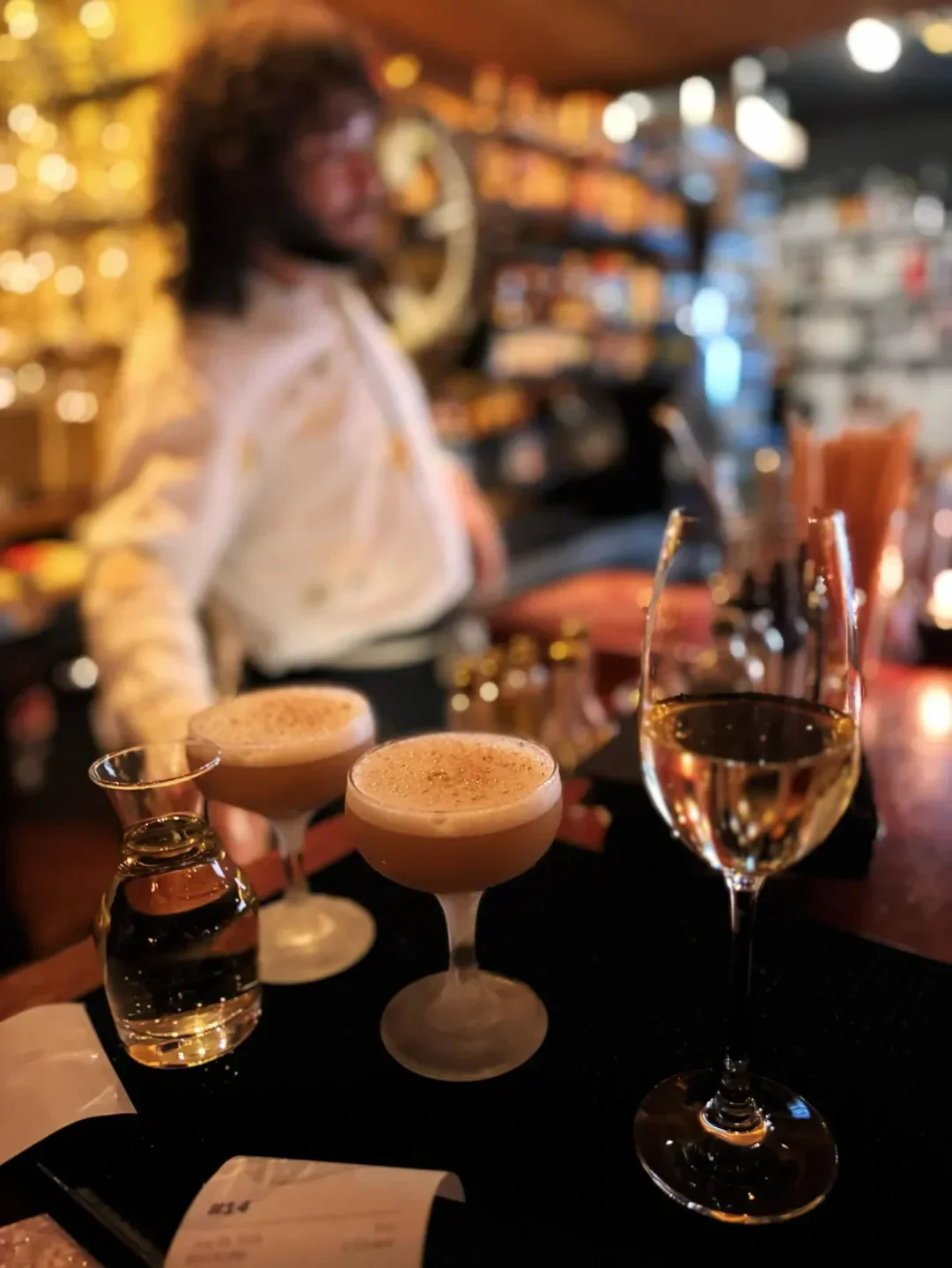 Cocktails and wine at Bramble & Hare restaurant in Boulder, Colorado, with a bartender in the background.