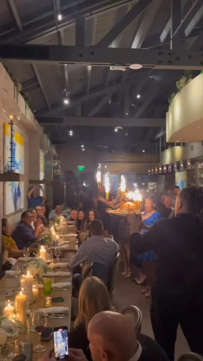 Celebratory ambiance at Broadway by Amar Santana restaurant in Orange County, featuring a cake with sparklers and happy diners.