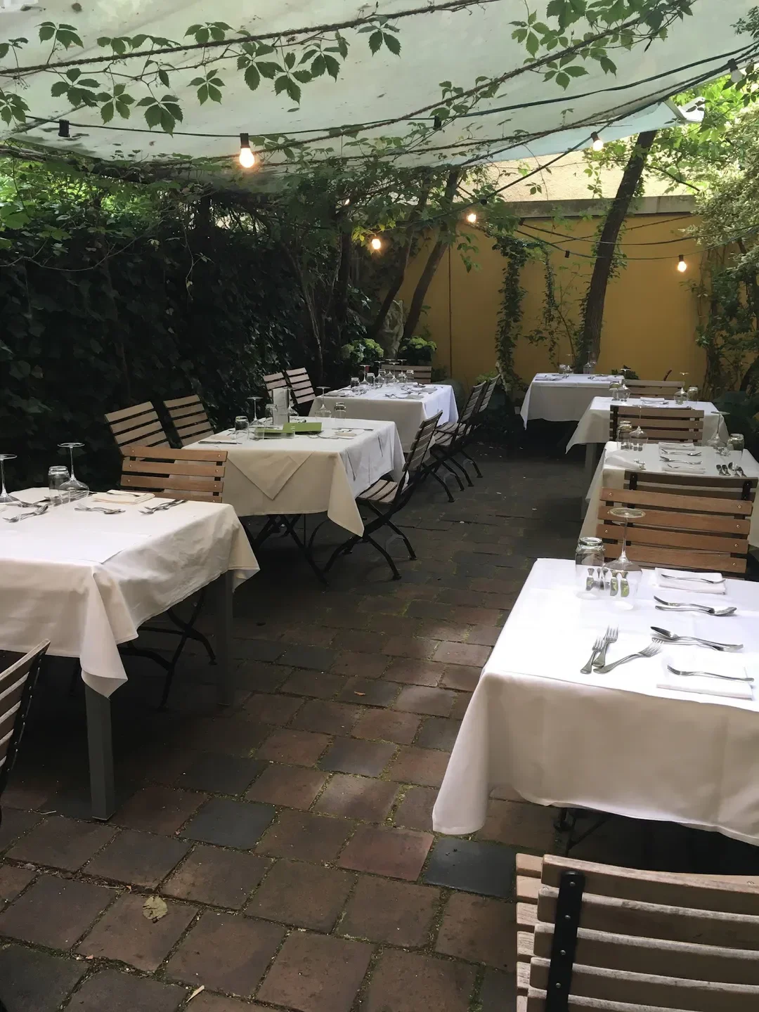 Outdoor dining area at Broeding restaurant in Munich, tables set for service.