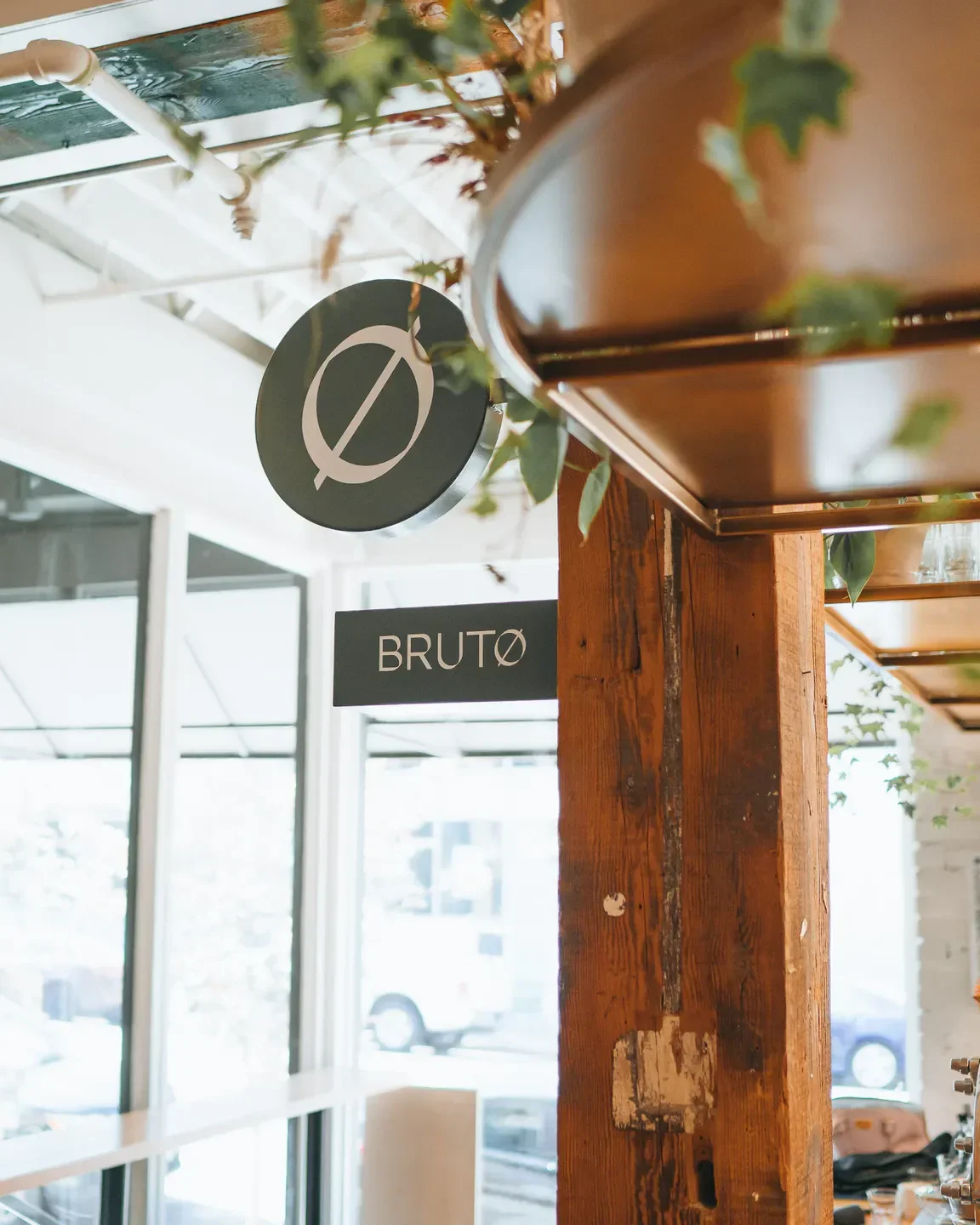 Signage and decor inside BRUTØ restaurant in Denver. Rustic wood pillar and hanging sign.
