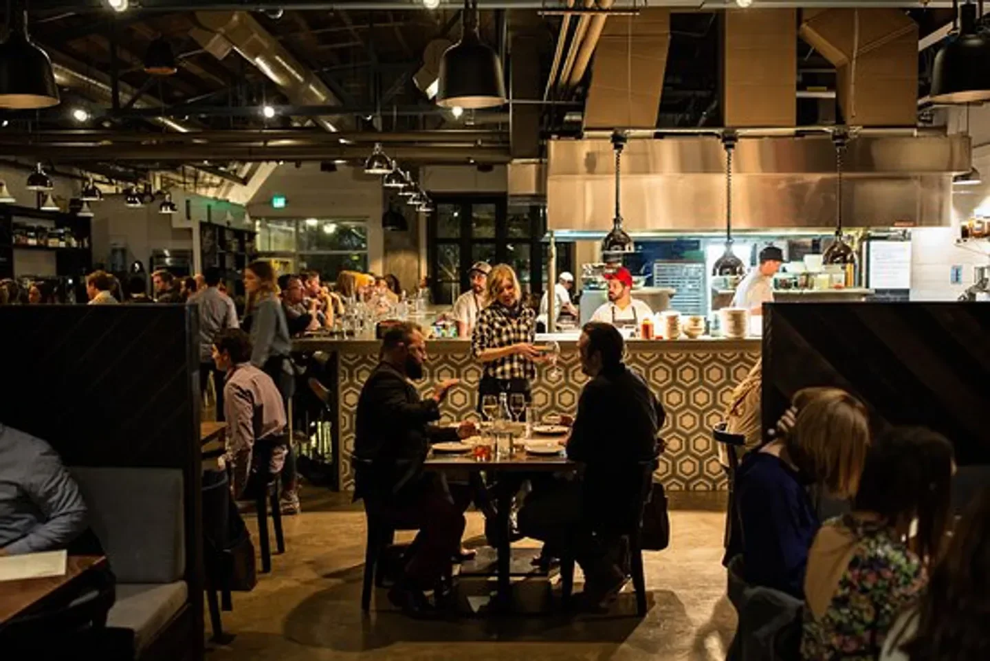 Interior of Butcher & Bee Nashville restaurant featuring customers and open kitchen.