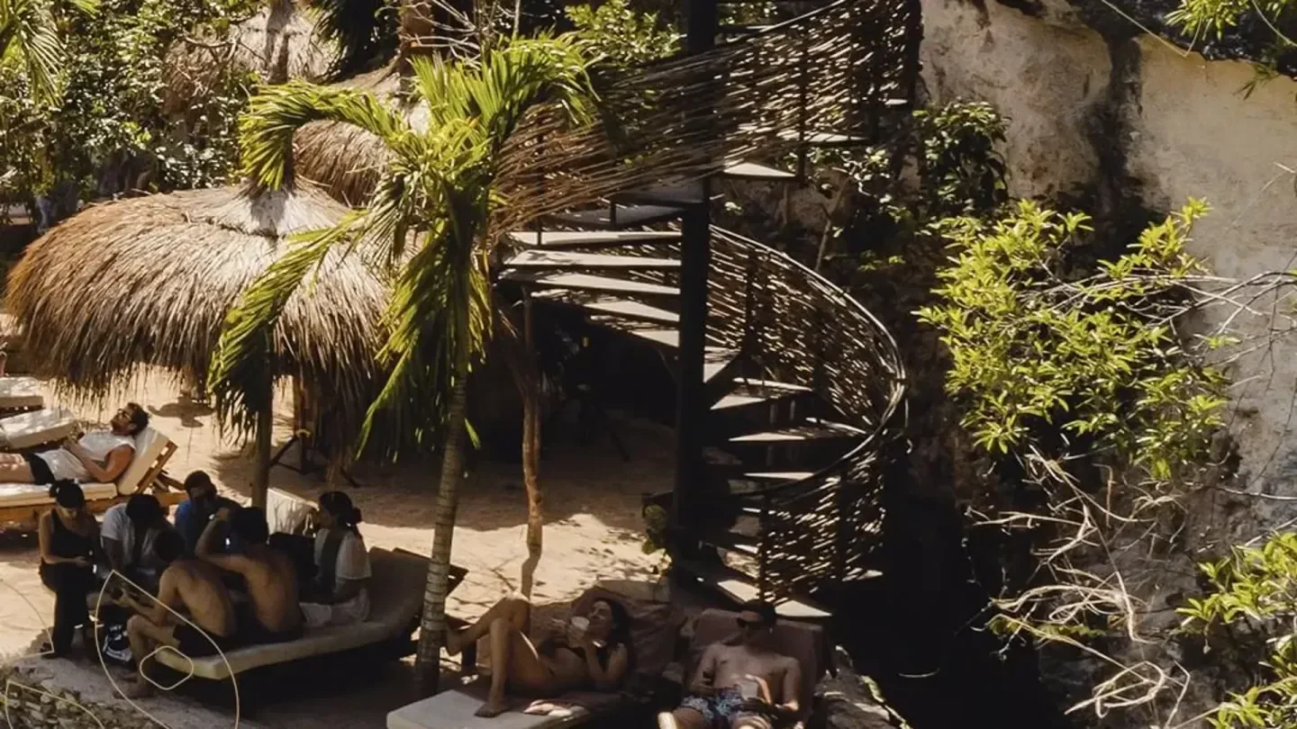 Relaxing beach day at Buuts HA in Tulum with spiral staircase and lush foliage.