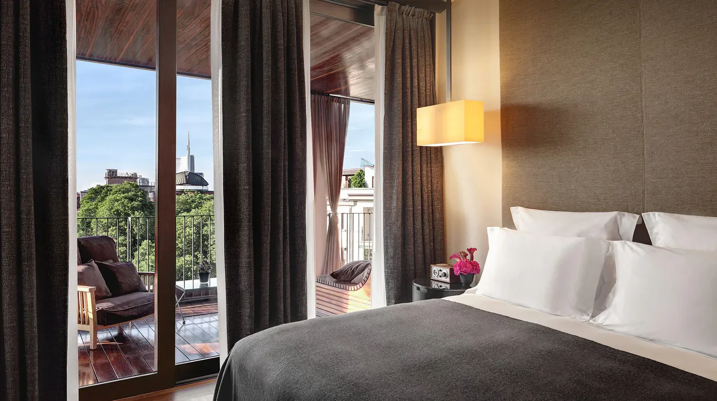 Cozy bedroom at Bvlgari Hotel Milan with balcony overlooking the city of Milan.