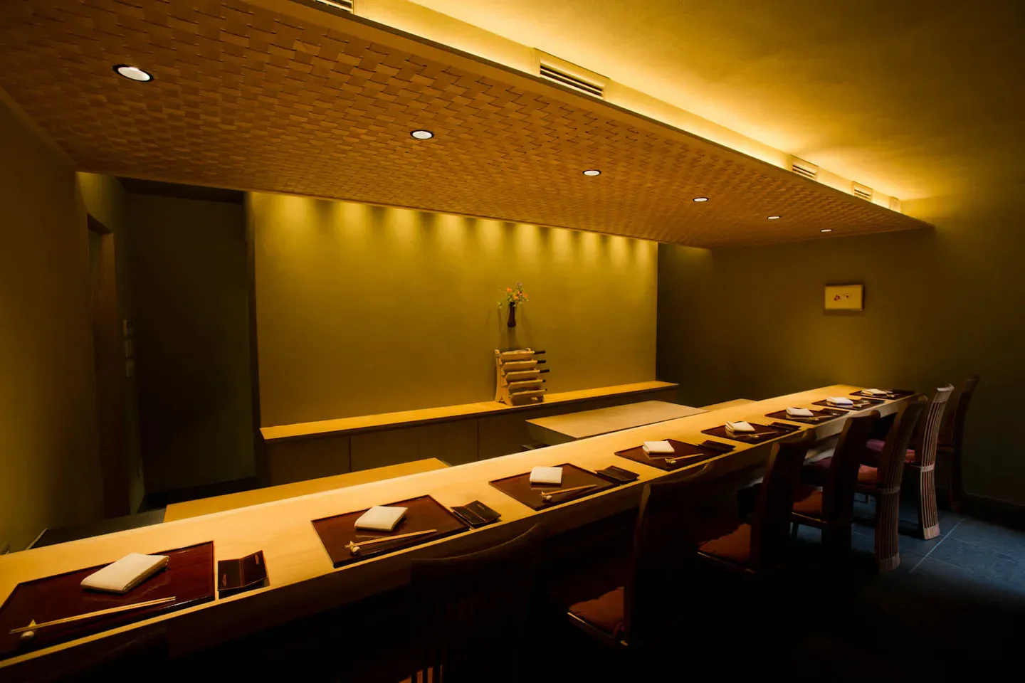 Elegant dining space at restaurant c in Kyoto, Japan, with wood and dim lighting.