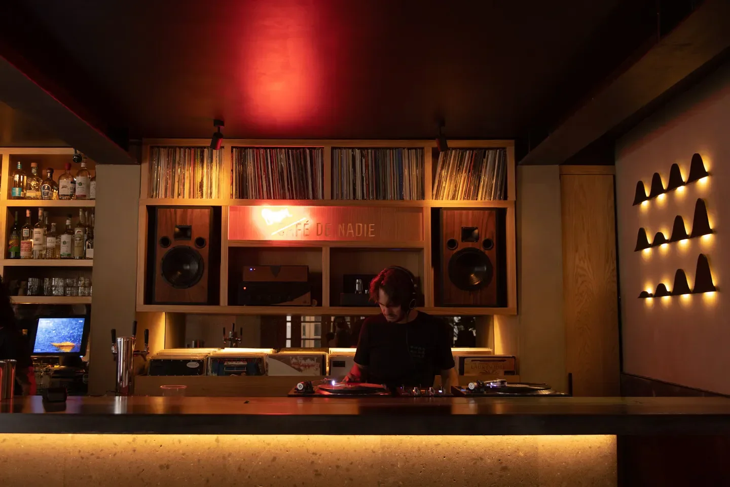 DJ at Café de Nadie in Mexico City, playing records behind the bar.