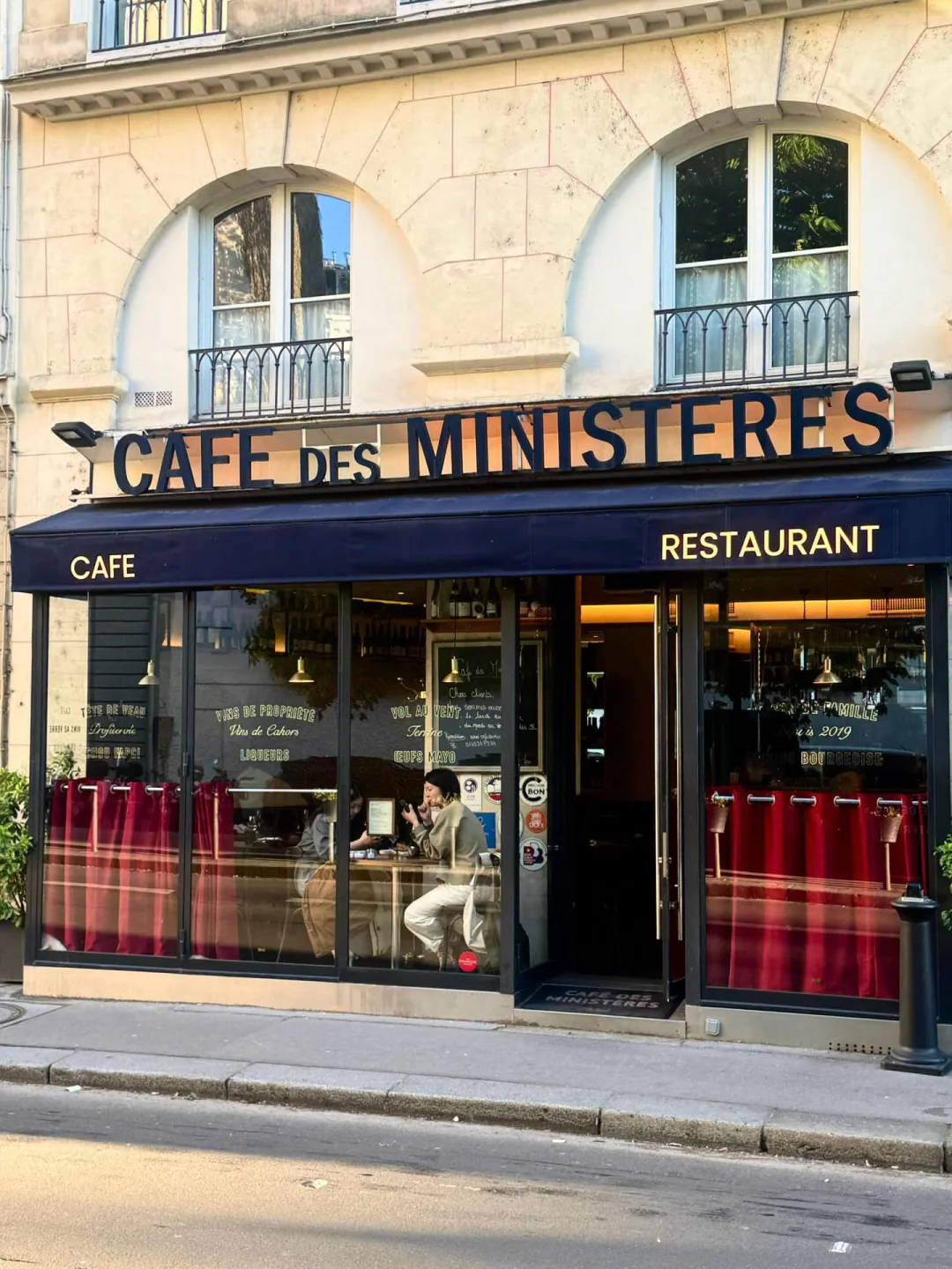 Café des Ministères restaurant exterior in Paris with red curtains visible through windows