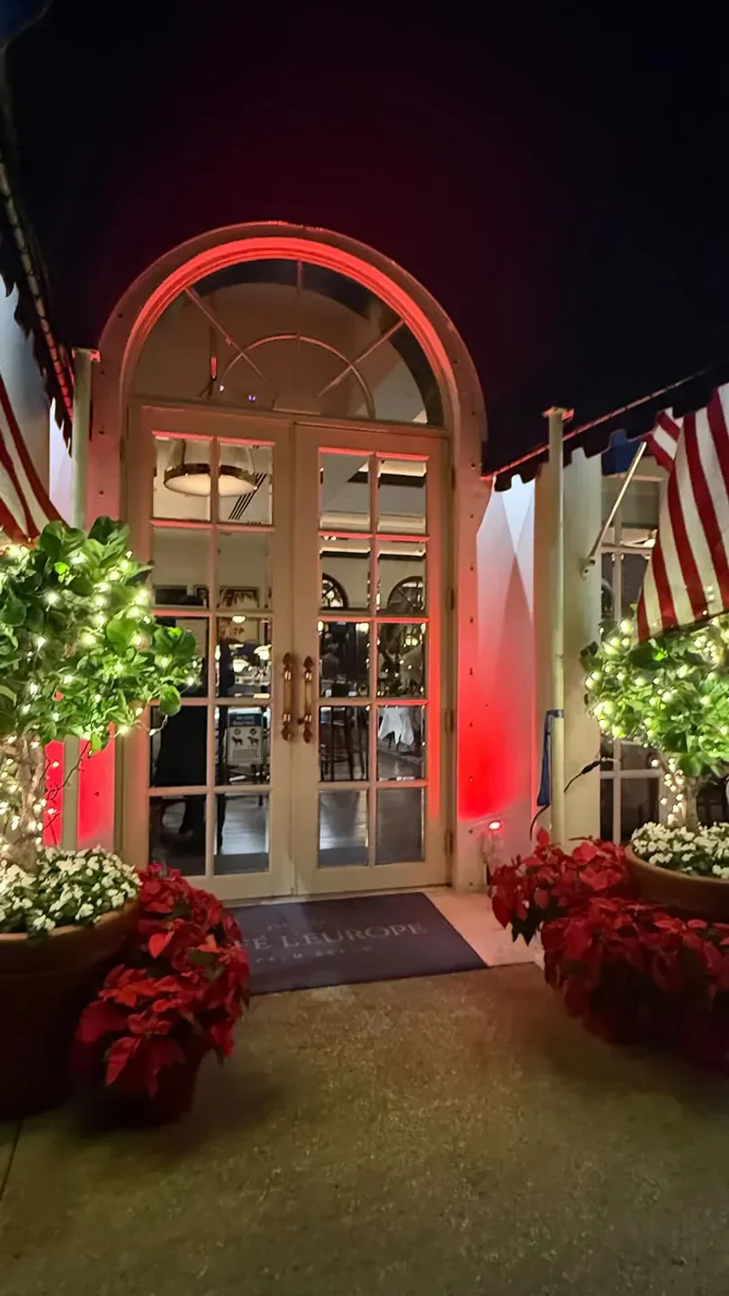 Entrance of Cafe L'Europe in Palm Beach at night, decorated with lights and flowers.