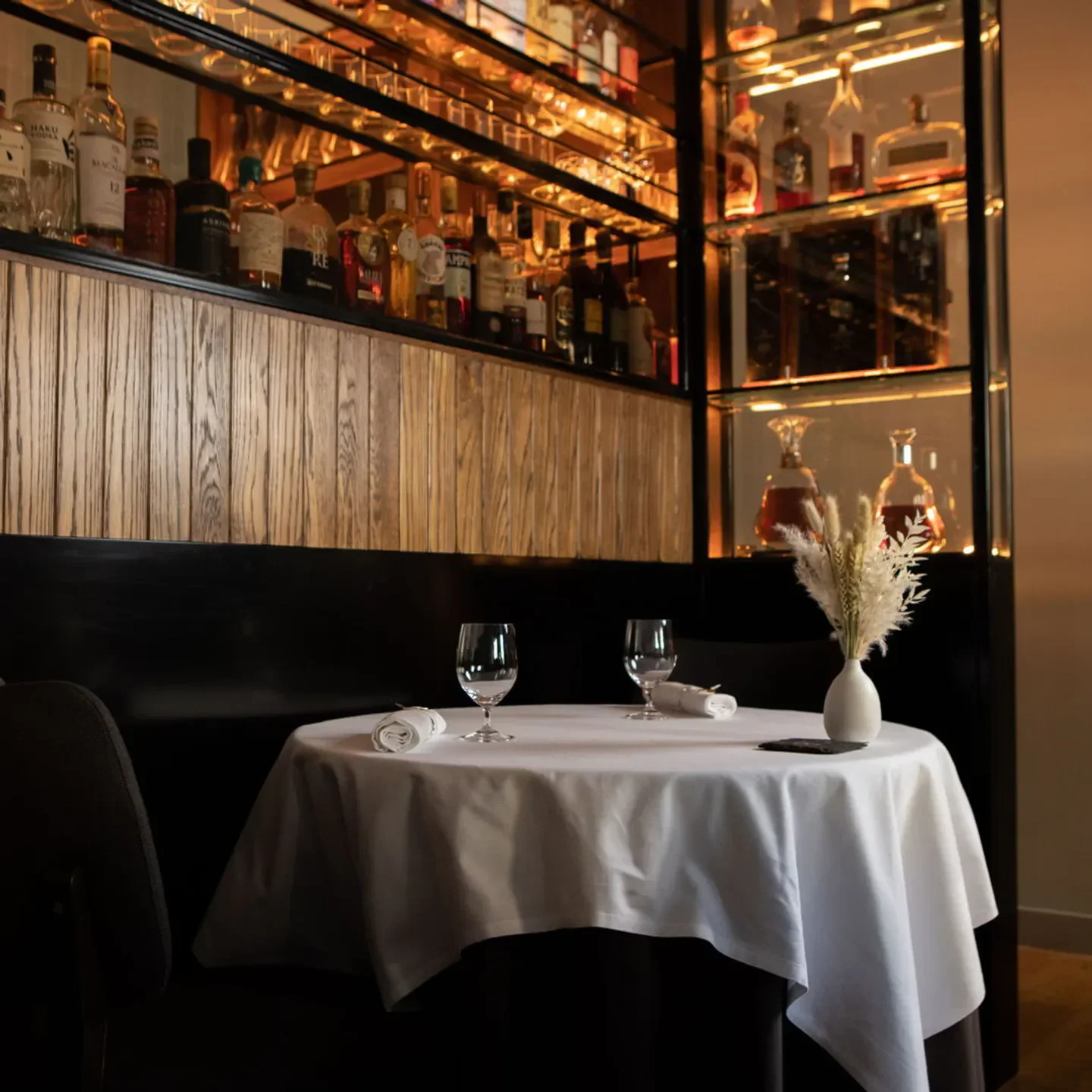 Elegant dining table at Cail Bruich restaurant in Glasgow, with spirits in the background.