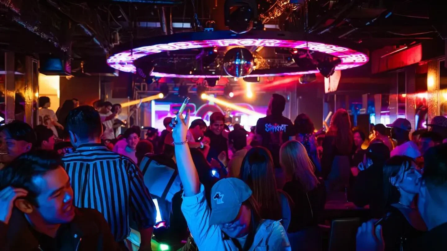 Energetic crowd partying inside Camelot nightclub in Tokyo with disco ball and lights