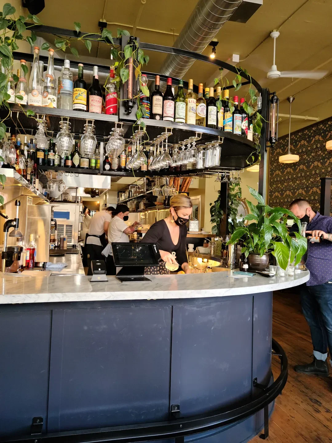 Interior view of Canard in Portland, with bar, shelves of liquor and hanging glasses.