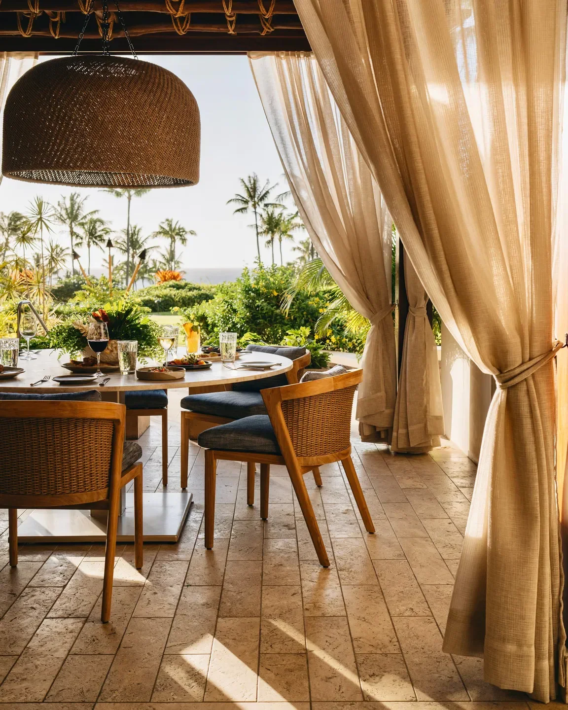 Outdoor dining at Cane & Canoe restaurant in Maui with ocean views and palm trees.