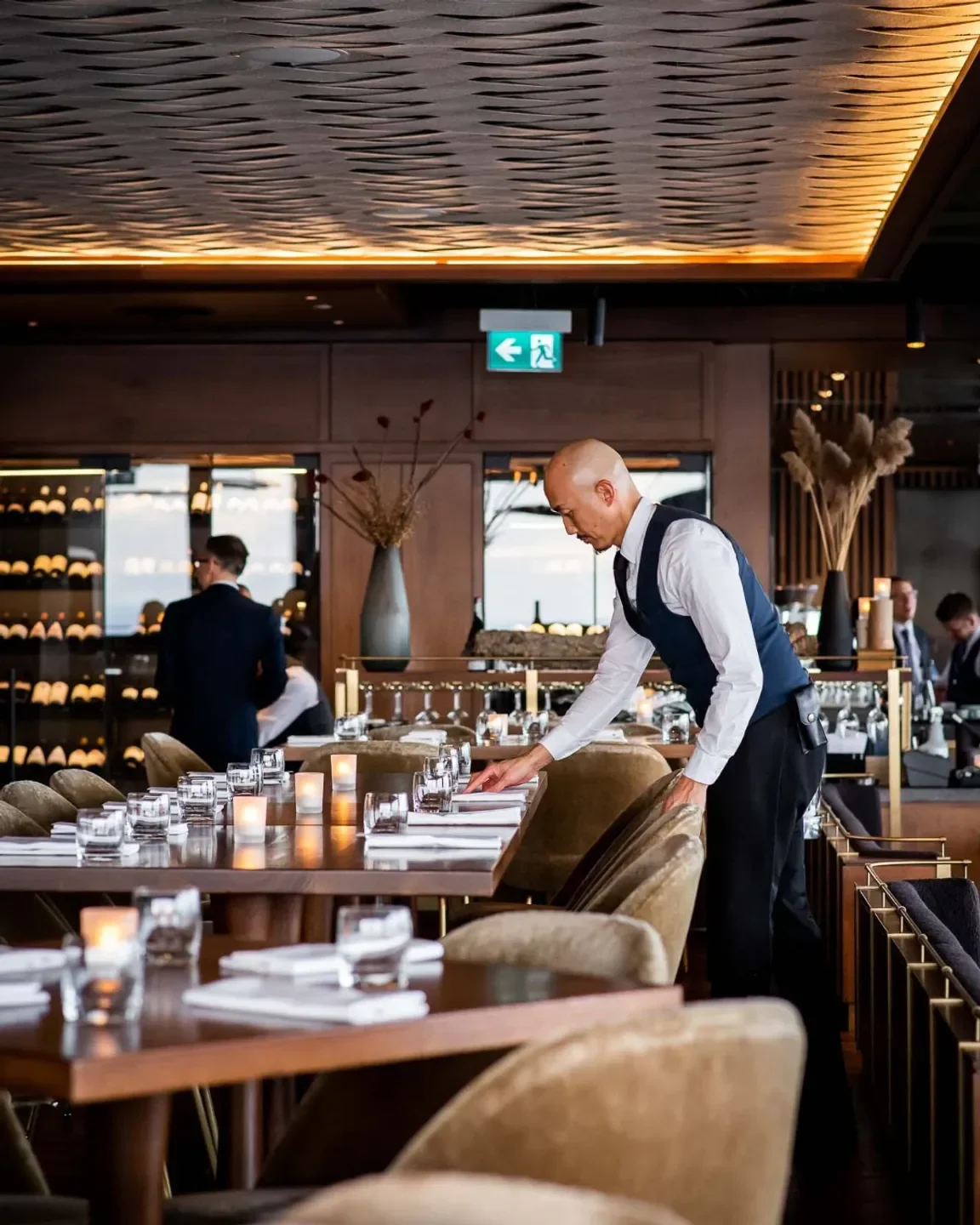 Server sets table at Canoe restaurant in Toronto, showcasing elegant interior details.
