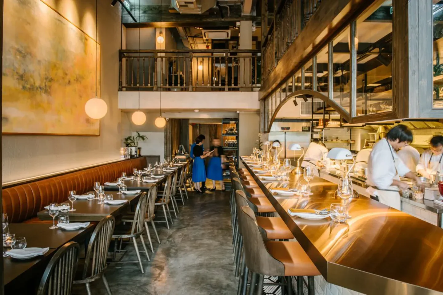 Interior of Canvas restaurant in Bangkok, showcasing bar, dining tables, and kitchen.