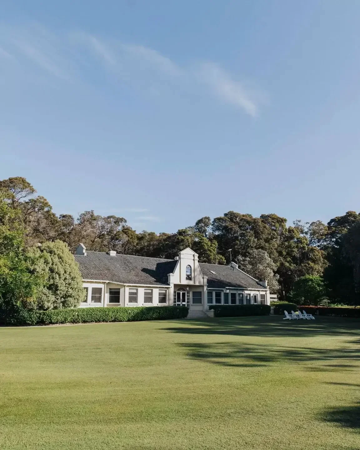 Exterior of Cape Lodge Restaurant in Margaret River, surrounded by lush green lawn and trees.