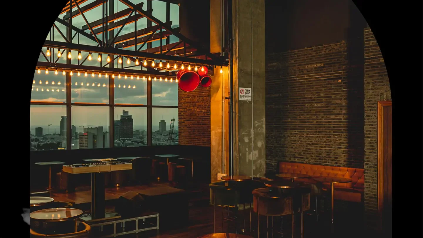 Capella Tel Aviv nightclub interior with city skyline view during sunset, brick wall.