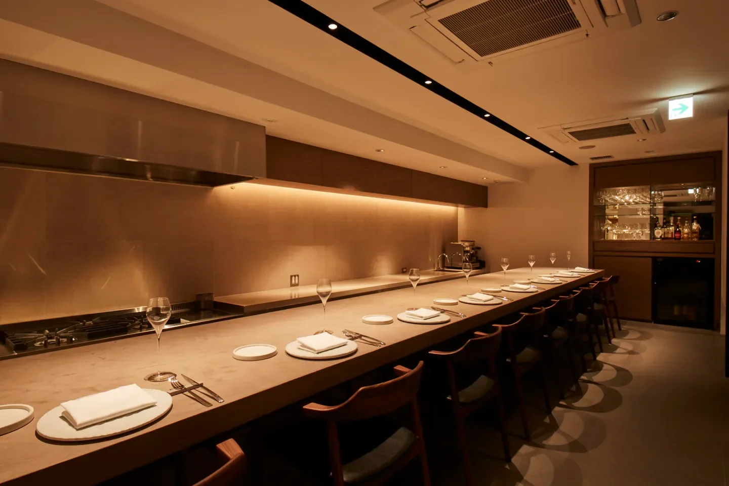 Dining space at capi restaurant in Osaka, Japan. Wooden chairs line the counter.