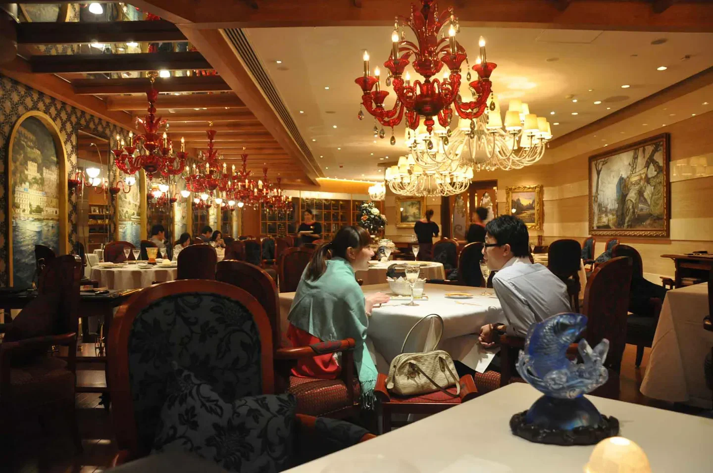 Elegant dining room at Casa Don Alfonso in Macau, featuring chandeliers and art.