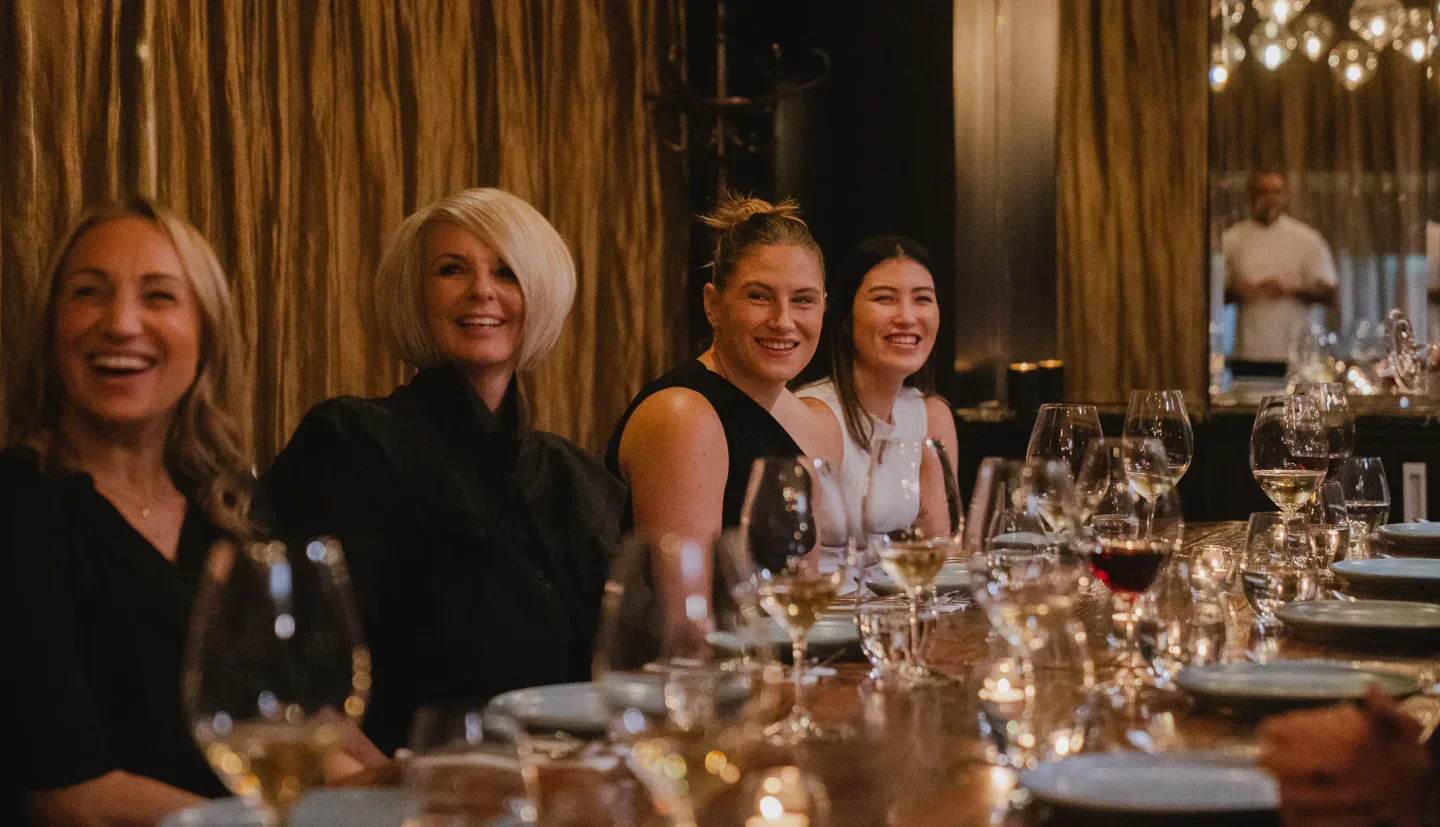 Happy diners at Cassia Auckland enjoying a meal with glasses of wine