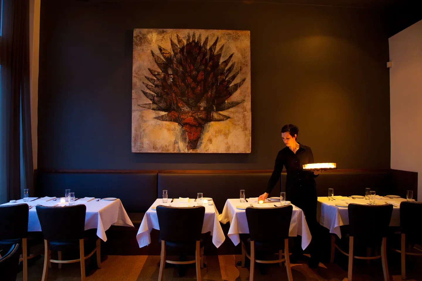 Elegant dining room at Castagna restaurant in Portland, with server preparing tables.