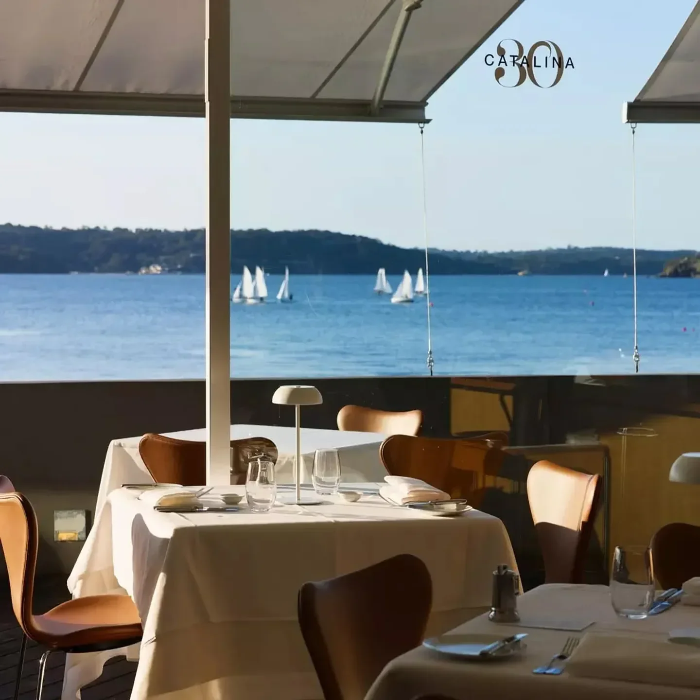 Catalina restaurant in Sydney with water views and sailboats in the background.