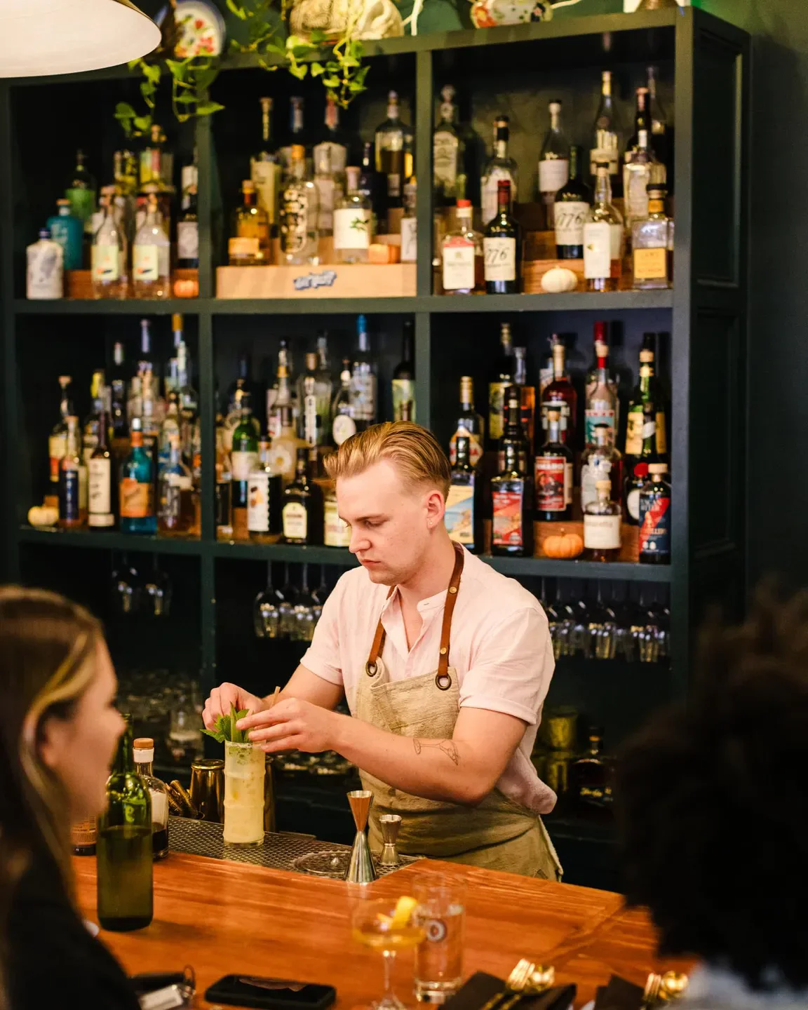 Bartender at Chubby Fish in Charleston preparing a cocktail with a fully stocked bar