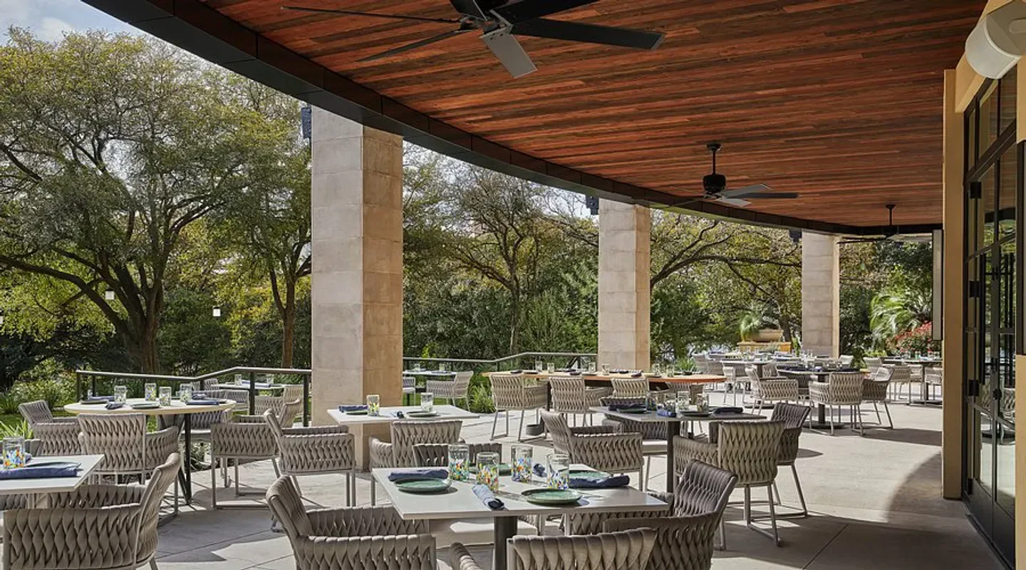 Outdoor dining at Ciclo in Austin, featuring tables and a view of surrounding trees.