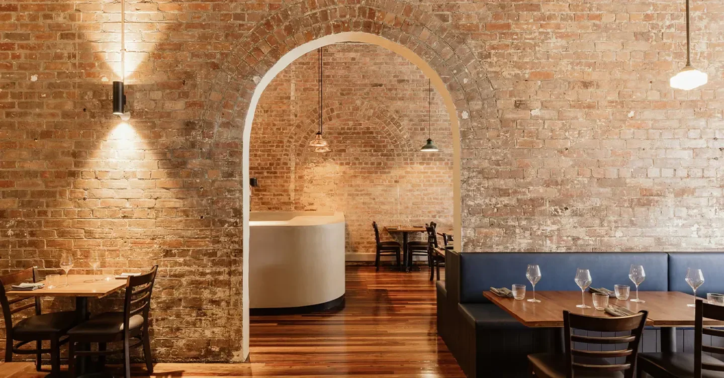Interior of Clarence Restaurant in Brisbane, with brick archway and dining tables.