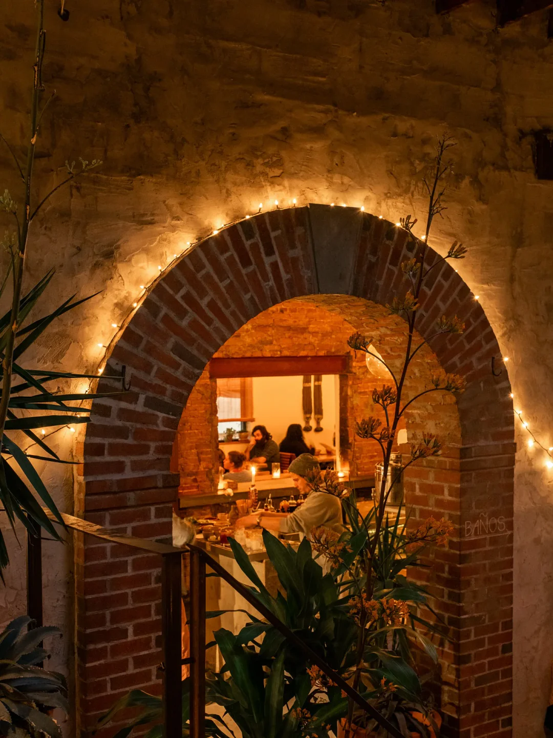 Cozy interior at Clavel Mezcaleria in Baltimore with brick archway and soft lighting, creating an inviting dining atmosphere.