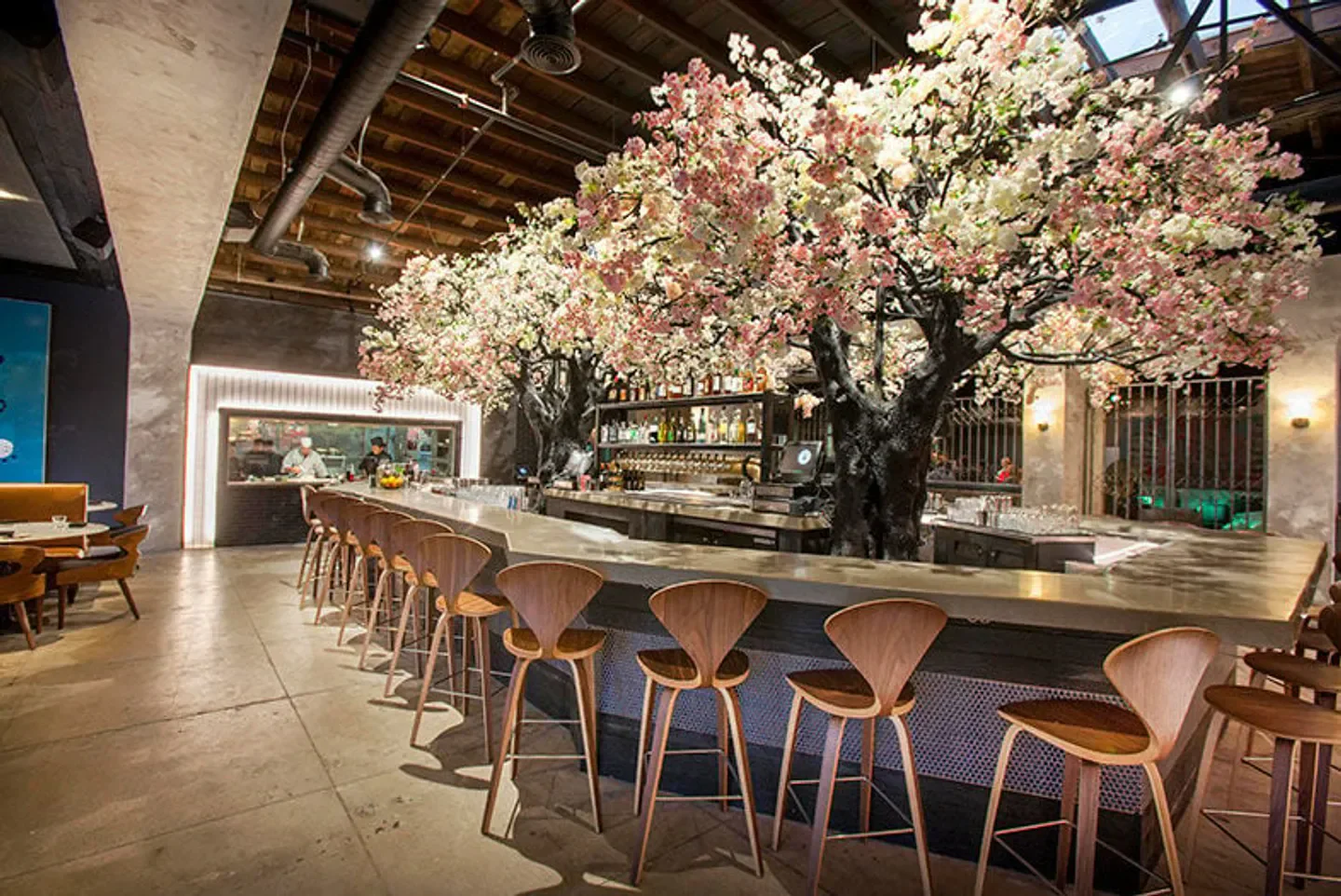 Interior of Cloak & Petal restaurant in San Diego featuring bar and cherry blossom trees.
