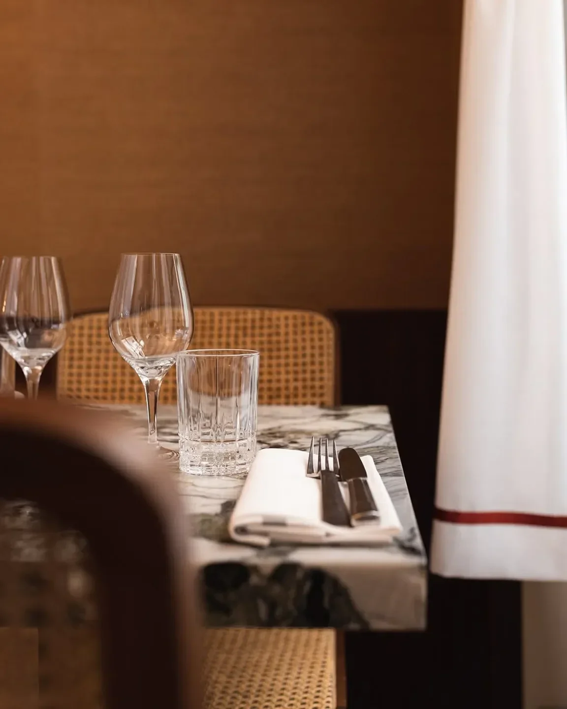 Table setting at Clover Grill in Paris, with glasses, cutlery, and a marble table.
