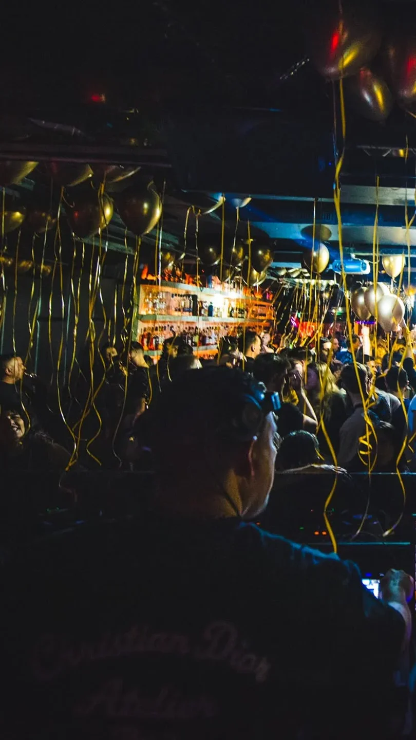 Energetic ambiance inside Club Prime in Amsterdam, showcasing a lively crowd and golden balloons at a nightclub event.