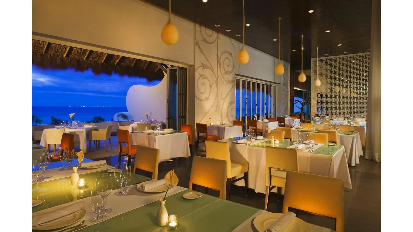 Cocina de Autor in Cabo San Lucas: elegant restaurant interior with ocean view at dusk.