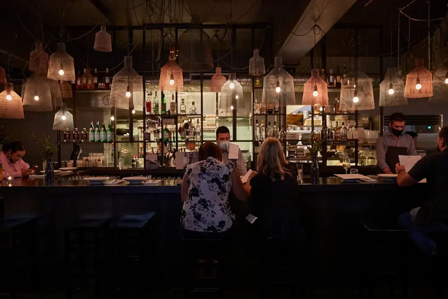 Interior of Coda restaurant in Melbourne with bar, overhead lights, and customers.